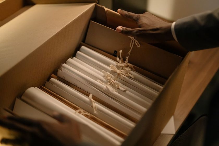 A hand writing a short numeric code on a folder tab