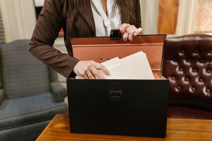 A cardboard box with loose papers sitting slightly open